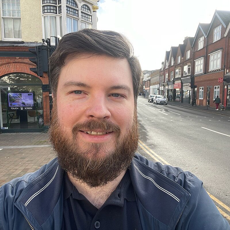 Image of the candidate Andrew Stevens, showing his head and shoulders, with the high street of Horley in the background.